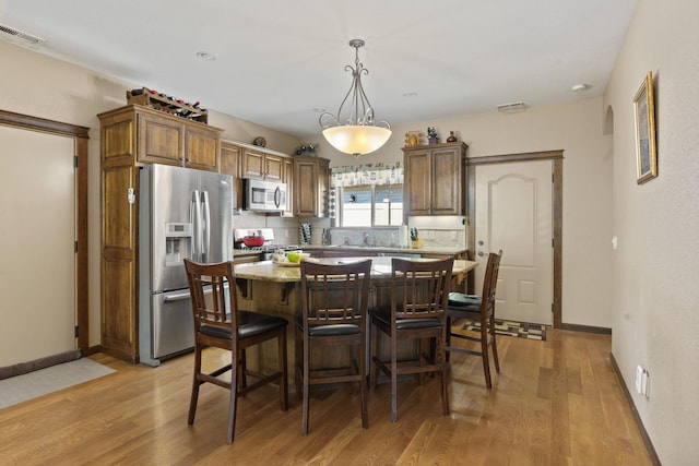 interior space featuring a kitchen island, hanging light fixtures, light hardwood / wood-style flooring, and appliances with stainless steel finishes