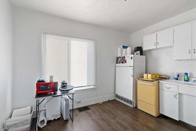 kitchen with white cabinets, dark hardwood / wood-style flooring, and white refrigerator