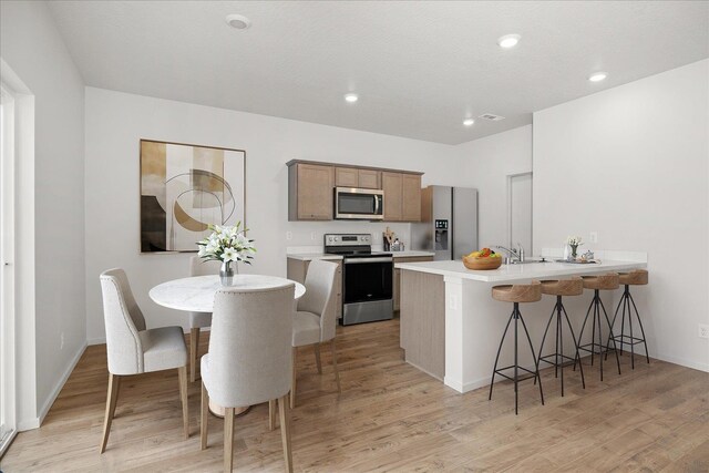 kitchen with light wood-type flooring, appliances with stainless steel finishes, and kitchen peninsula