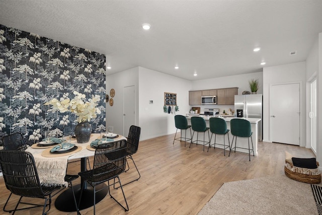 dining area with a textured ceiling and light hardwood / wood-style floors