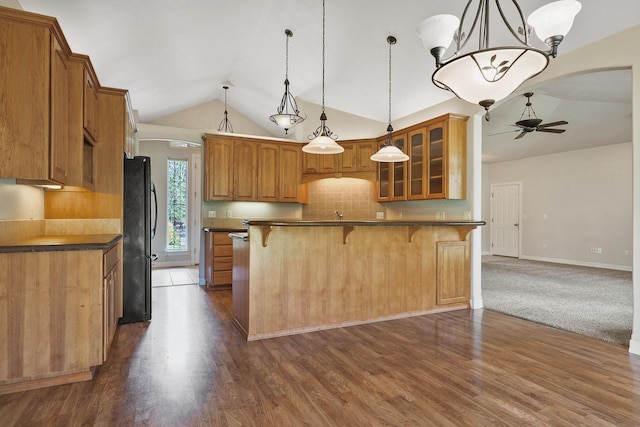 kitchen featuring glass insert cabinets, a kitchen bar, freestanding refrigerator, arched walkways, and a ceiling fan