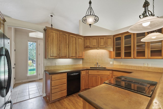 kitchen featuring a sink, black appliances, brown cabinetry, and vaulted ceiling