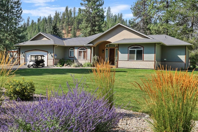 ranch-style house featuring a garage, roof with shingles, and a front yard