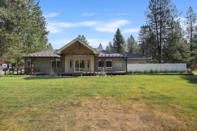 back of property featuring a deck, a yard, and fence