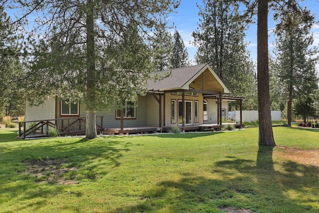 rear view of property with a lawn, a deck, and fence