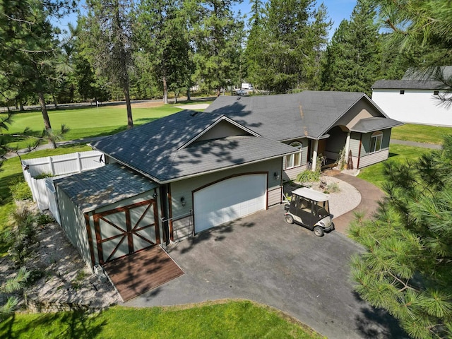 view of front of house with a shingled roof, a front lawn, fence, driveway, and an attached garage