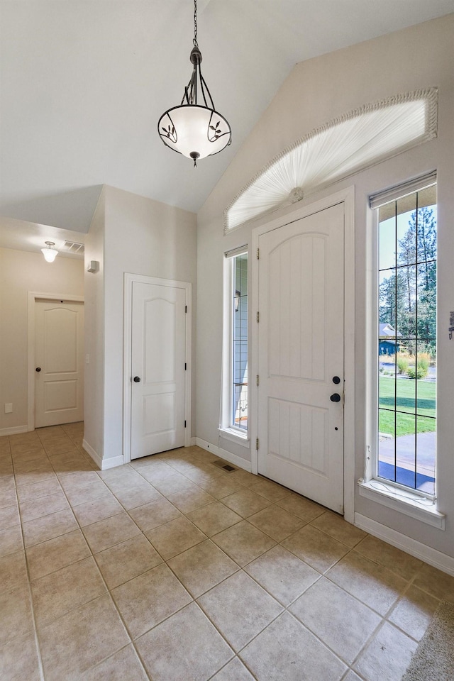 foyer entrance featuring light tile patterned flooring, visible vents, baseboards, and vaulted ceiling