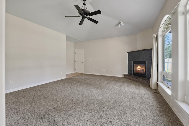 unfurnished living room featuring carpet, baseboards, a ceiling fan, lofted ceiling, and a glass covered fireplace
