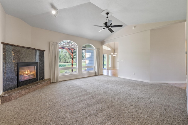 unfurnished living room with baseboards, a high end fireplace, vaulted ceiling, carpet flooring, and ceiling fan with notable chandelier