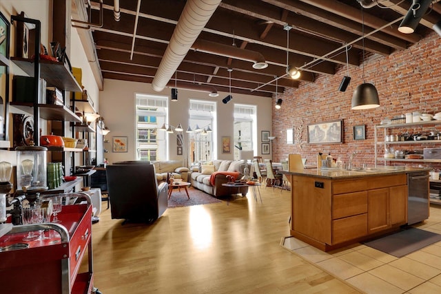 kitchen with brick wall, stone countertops, sink, and light wood-type flooring