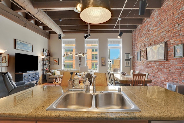 kitchen with a towering ceiling, brick wall, and sink