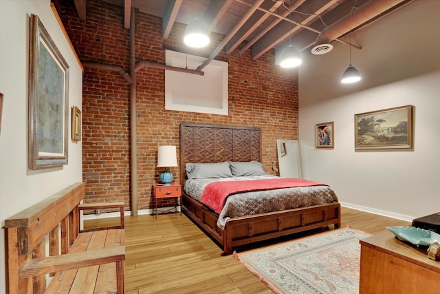 bedroom featuring brick wall and light hardwood / wood-style flooring