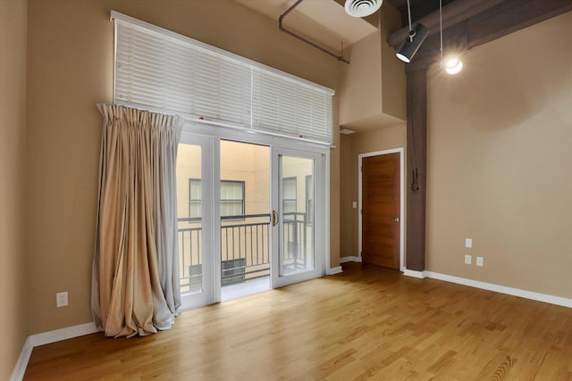 unfurnished room with light hardwood / wood-style floors and a high ceiling