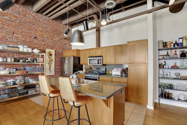 kitchen featuring sink, stainless steel appliances, an island with sink, and a kitchen bar