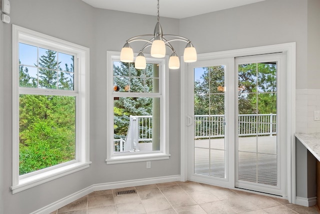 doorway featuring a healthy amount of sunlight, light tile patterned floors, baseboards, and a notable chandelier