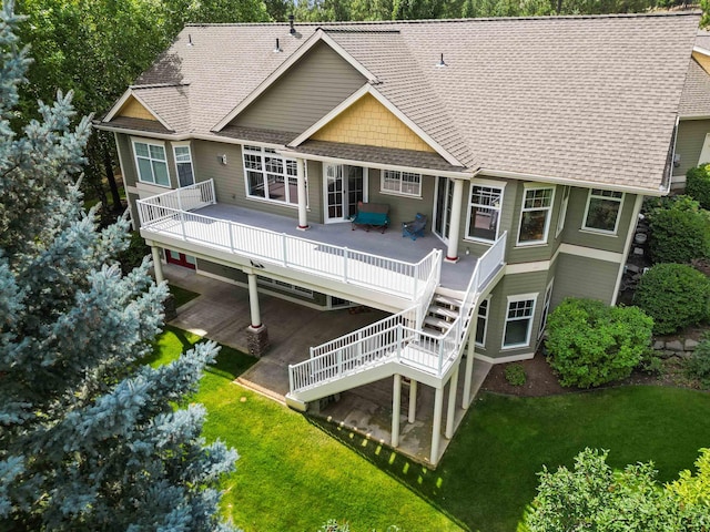 back of property with a yard, stairway, roof with shingles, and a wooden deck