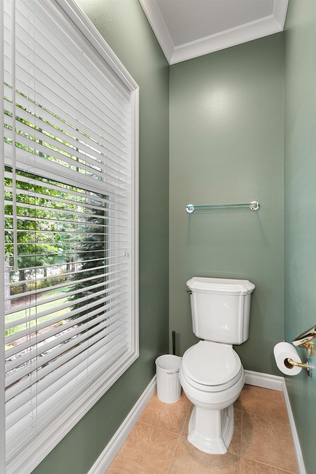 half bathroom with toilet, tile patterned flooring, baseboards, and crown molding