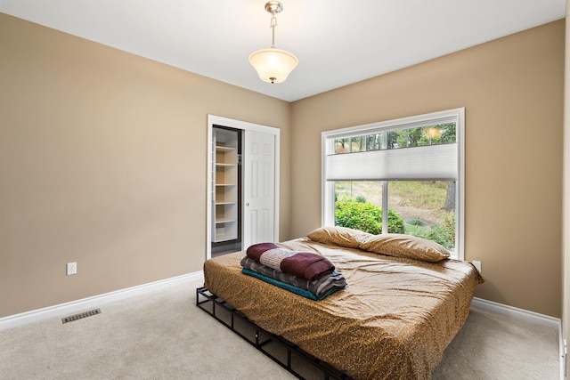 bedroom featuring baseboards, a closet, visible vents, and light colored carpet