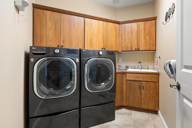 clothes washing area with cabinet space, light tile patterned floors, baseboards, washer and dryer, and a sink