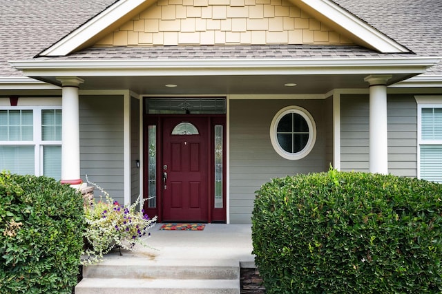 view of exterior entry featuring roof with shingles