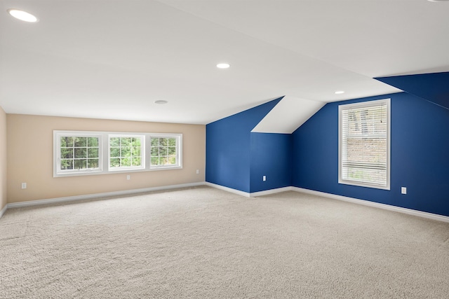 additional living space with recessed lighting, light colored carpet, vaulted ceiling, and baseboards