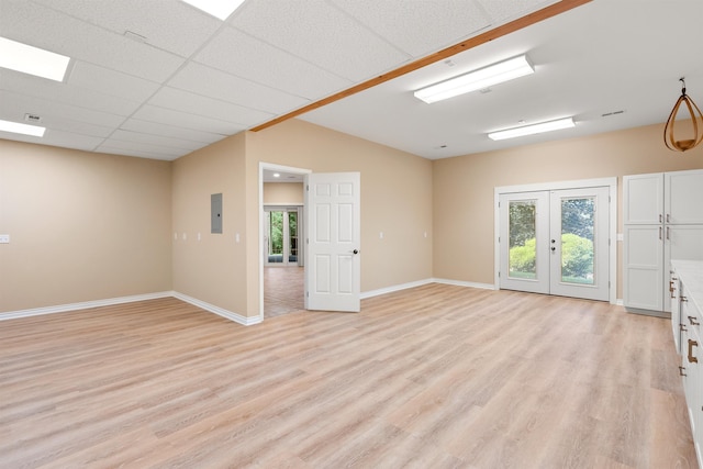 unfurnished room with light wood-type flooring, electric panel, baseboards, and french doors