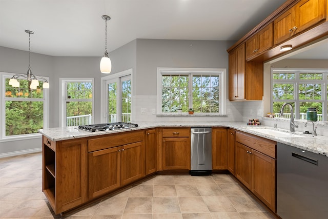 kitchen with a peninsula, pendant lighting, brown cabinetry, and a sink