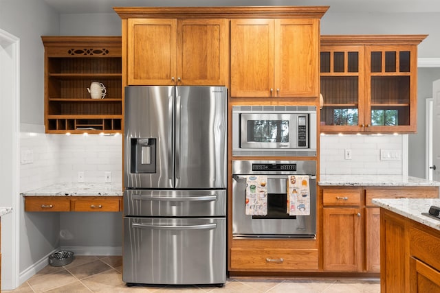 kitchen with light tile patterned floors, tasteful backsplash, light stone counters, and stainless steel appliances