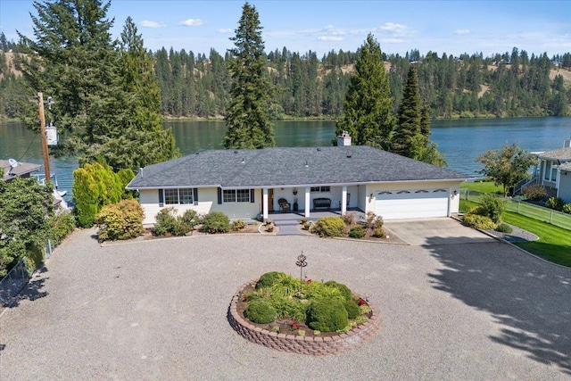 single story home with a water view, driveway, and a view of trees