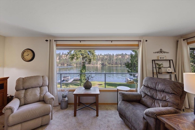 sitting room with baseboards, a water view, and light colored carpet