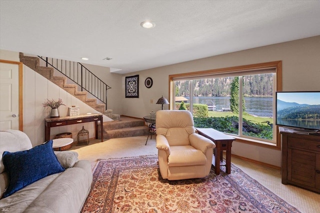 living area with light colored carpet, a textured ceiling, baseboards, and stairs