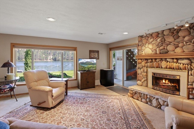 living room with a textured ceiling, baseboards, a stone fireplace, and light colored carpet