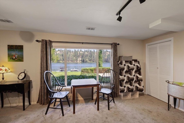 living area featuring visible vents, a water view, light carpet, and baseboards