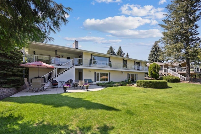 rear view of property featuring a chimney, a yard, stairway, and a patio area