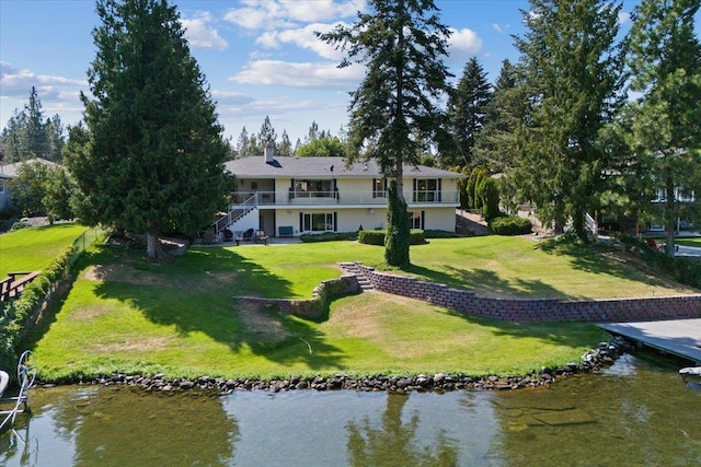 rear view of property with a water view, a chimney, and a lawn