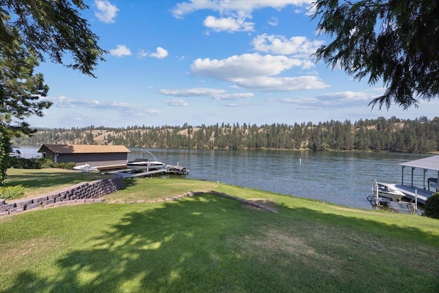 view of dock with a water view, a yard, and a forest view