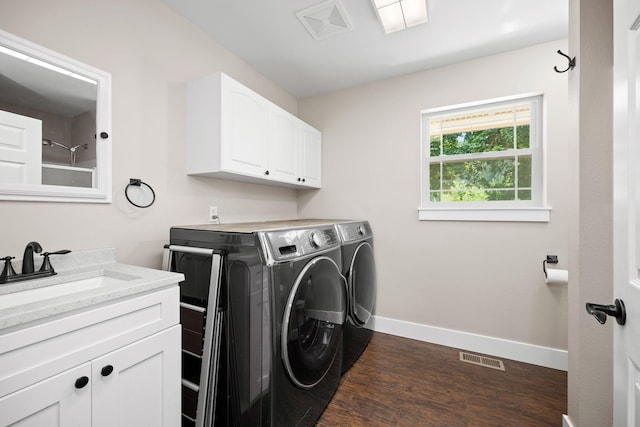 clothes washing area with sink, dark wood-type flooring, cabinets, and washing machine and clothes dryer