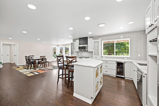 kitchen with backsplash, wine cooler, appliances with stainless steel finishes, and a healthy amount of sunlight