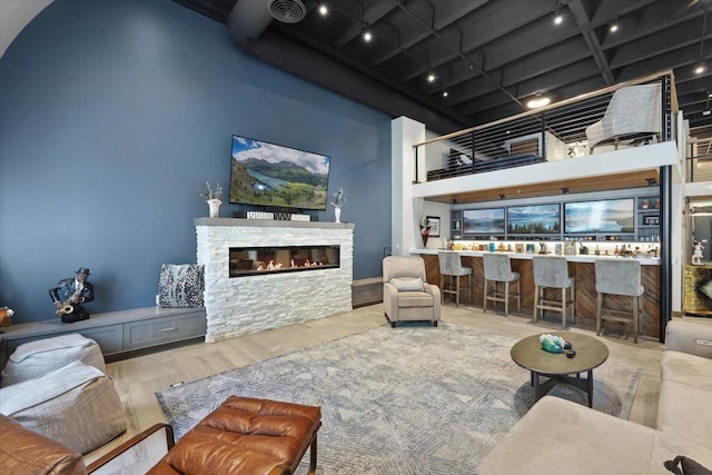 living room featuring light hardwood / wood-style floors, a towering ceiling, coffered ceiling, and a fireplace