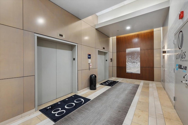 interior space featuring a towering ceiling, light tile patterned flooring, and elevator