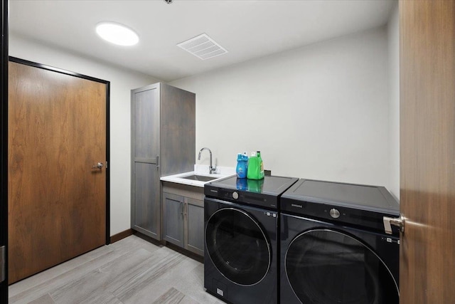 laundry room with sink, washing machine and dryer, and cabinets