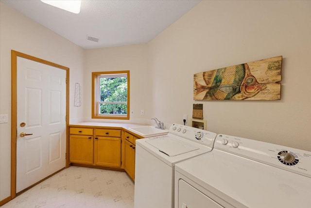 washroom featuring separate washer and dryer, a sink, visible vents, cabinet space, and light floors