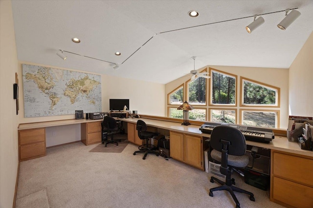 office space with built in desk, recessed lighting, rail lighting, light colored carpet, and vaulted ceiling