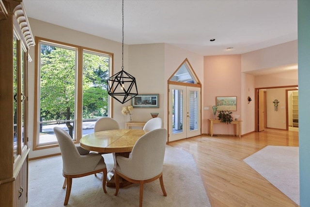 dining space featuring french doors, light wood-type flooring, a wealth of natural light, and baseboards