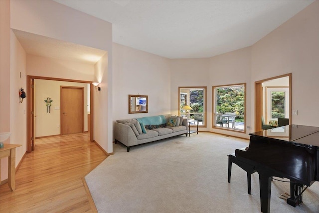 living area featuring baseboards, light wood-style flooring, and a towering ceiling