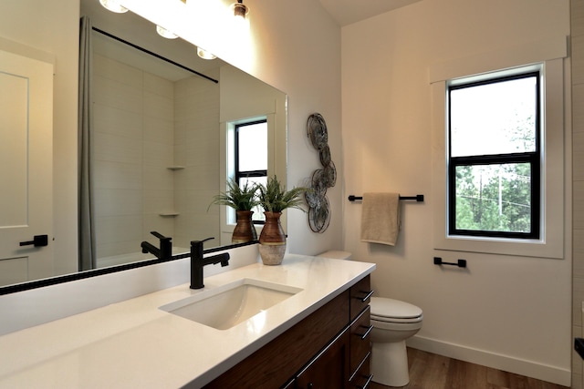 bathroom with hardwood / wood-style floors, toilet, and a healthy amount of sunlight