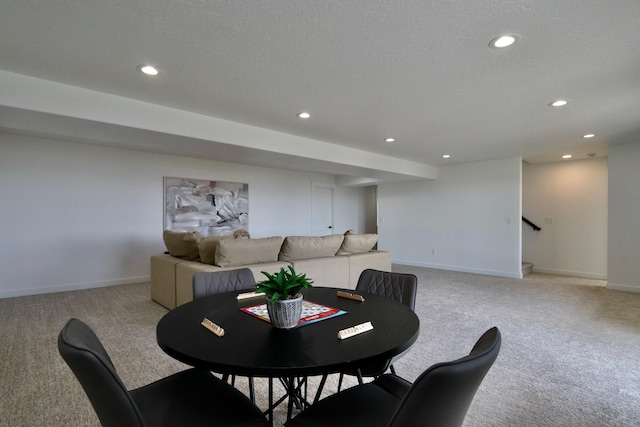 dining space with a textured ceiling and light carpet