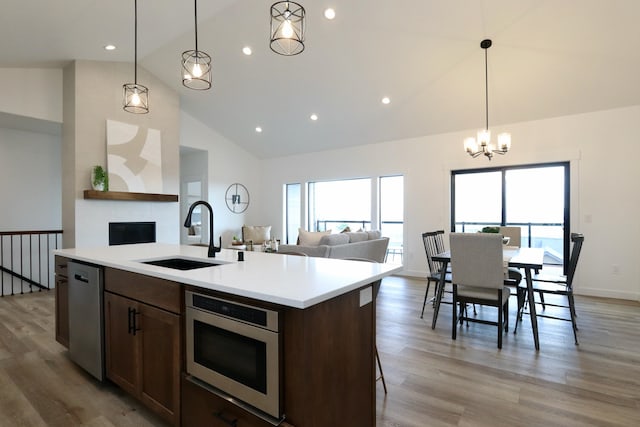 kitchen with sink, light hardwood / wood-style flooring, a chandelier, stainless steel appliances, and pendant lighting