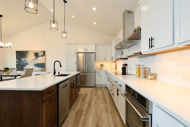 kitchen featuring appliances with stainless steel finishes, backsplash, sink, light wood-type flooring, and wall chimney range hood