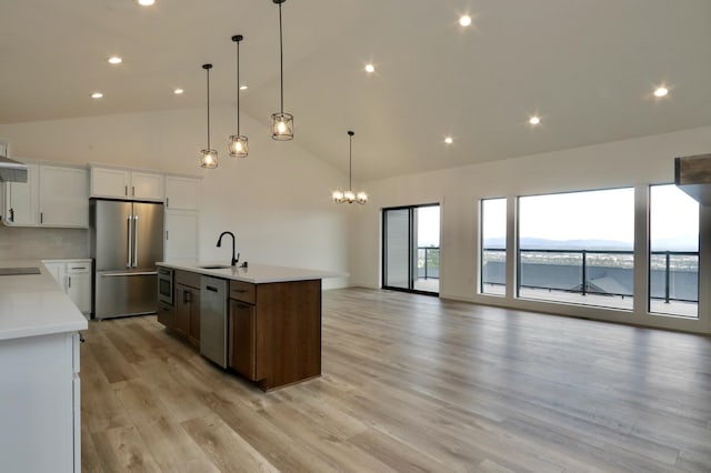 kitchen with backsplash, appliances with stainless steel finishes, light hardwood / wood-style floors, white cabinetry, and a center island with sink